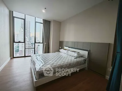 Modern bedroom with large windows and city view in high-rise apartment