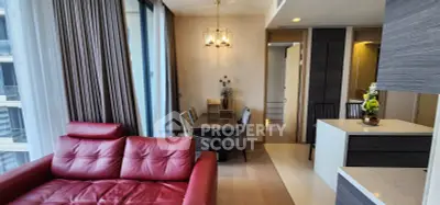 Modern living room with red leather sofa and elegant dining area in a high-rise apartment.