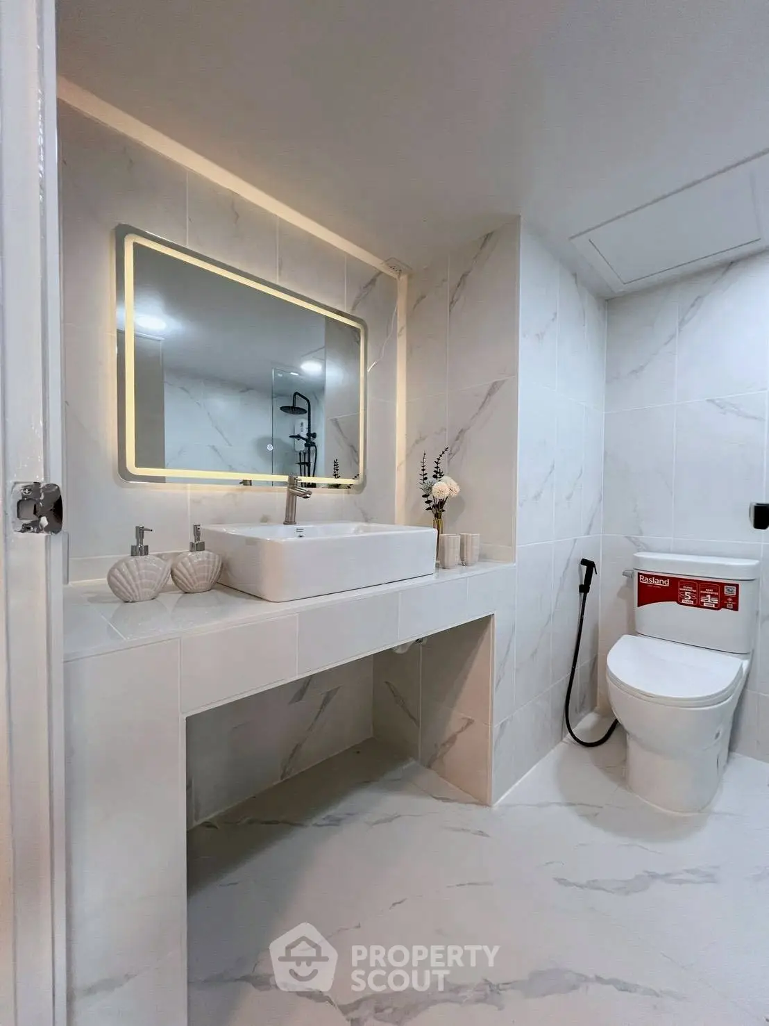 Modern bathroom with elegant marble tiles and illuminated mirror