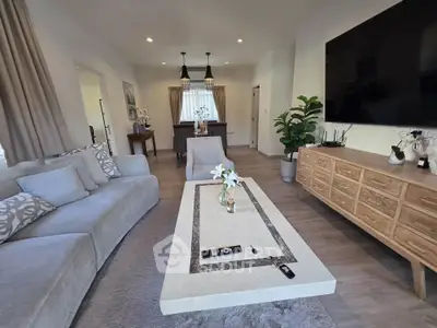 Elegant living room with modern decor, large TV, and stylish furniture, perfect for relaxation and entertainment.
