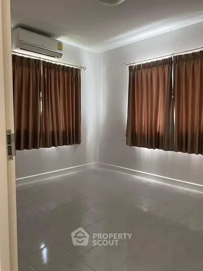 Spacious empty room with tiled floor and air conditioning, ideal for customization.