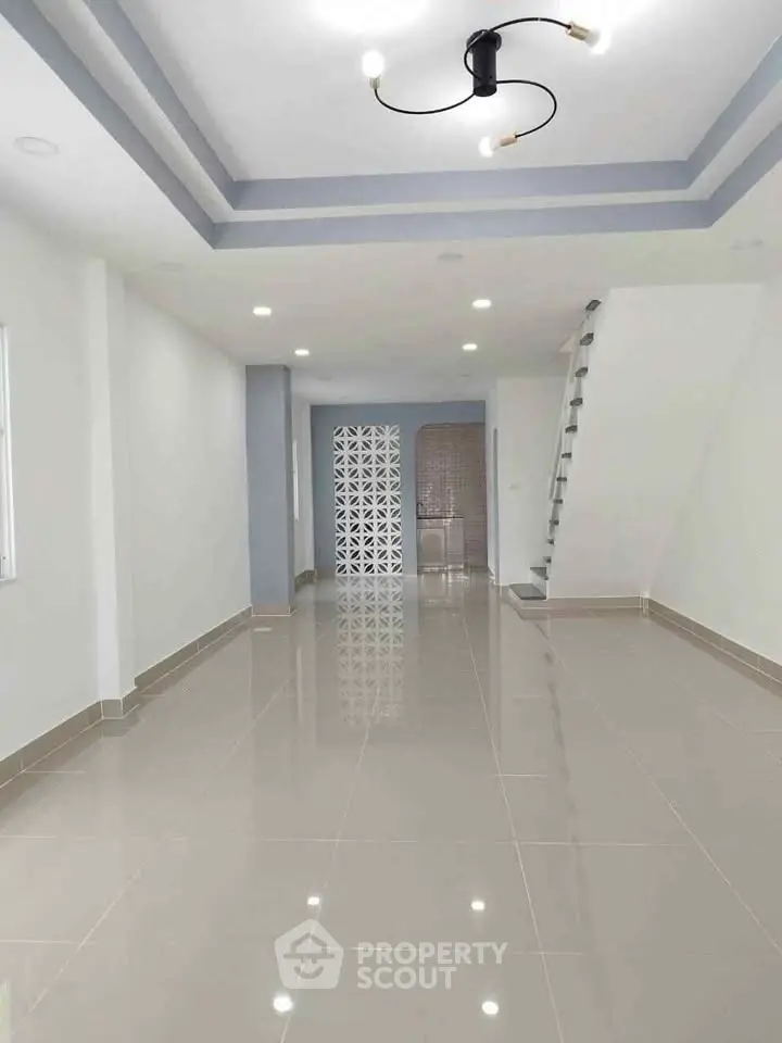 Spacious modern living room with glossy tiled floors and stylish ceiling lights.