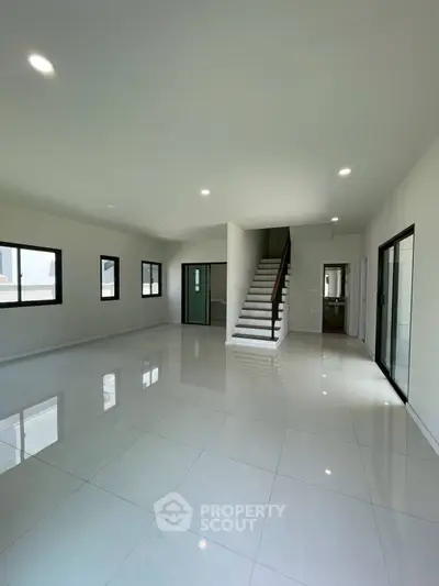 Spacious modern living room with glossy tile flooring and staircase