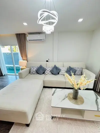 Modern living room with elegant decor and pool view, featuring a stylish sectional sofa and chic lighting.
