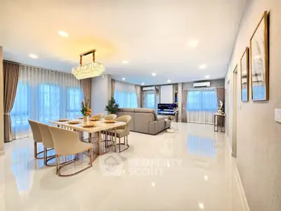 Luxurious open-plan living and dining area with elegant chandelier and modern decor.