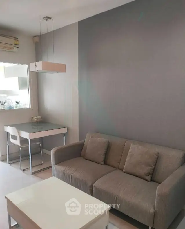 Modern living room with sleek gray sofa and stylish dining area in open layout apartment.