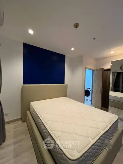 Modern bedroom with stylish blue accent wall and comfortable bed in contemporary apartment.