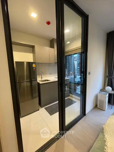 Modern kitchen with sleek appliances and balcony view in stylish apartment.