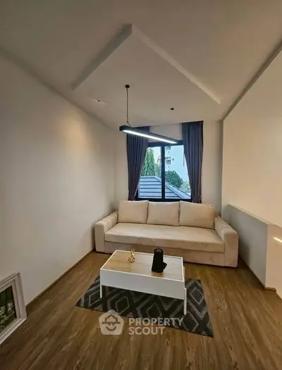 Modern living room with cozy sofa and stylish lighting, featuring a large window with a view.