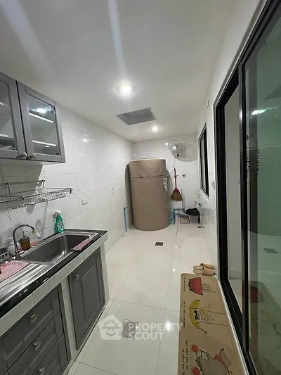 Modern kitchen with sleek cabinetry and stainless steel sink, featuring a compact layout and bright lighting.