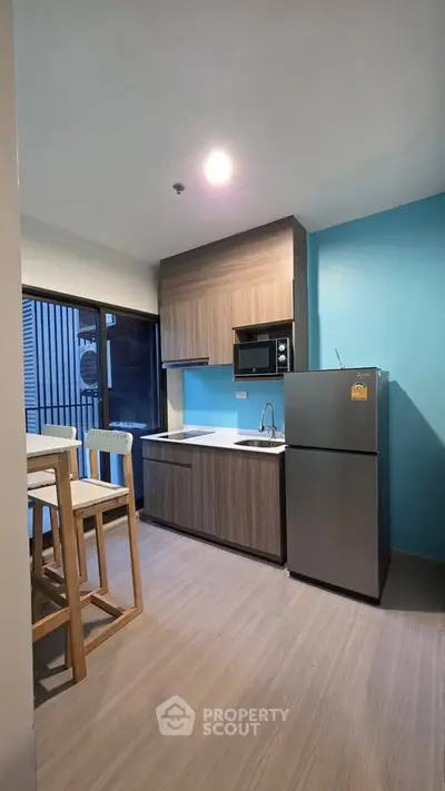 Modern kitchen with sleek design, featuring a fridge, microwave, and stylish cabinetry.