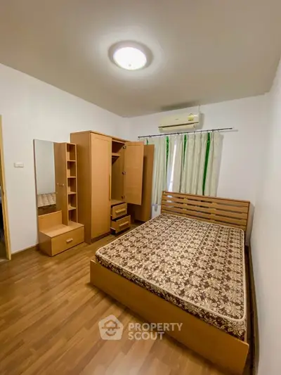 Cozy bedroom with wooden furniture and air conditioning, perfect for comfort and relaxation.
