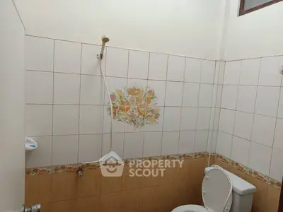 Cozy bathroom with floral tile design and showerhead, ideal for compact living spaces.