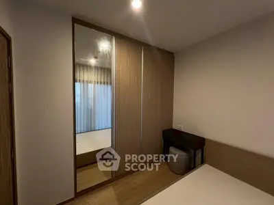 Modern bedroom with mirrored wardrobe and sleek wooden furniture