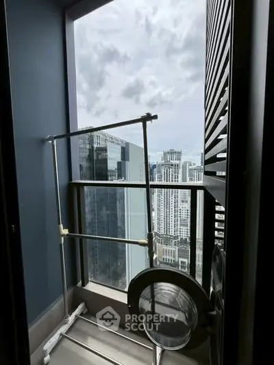 High-rise apartment balcony with city skyline view and laundry rack.