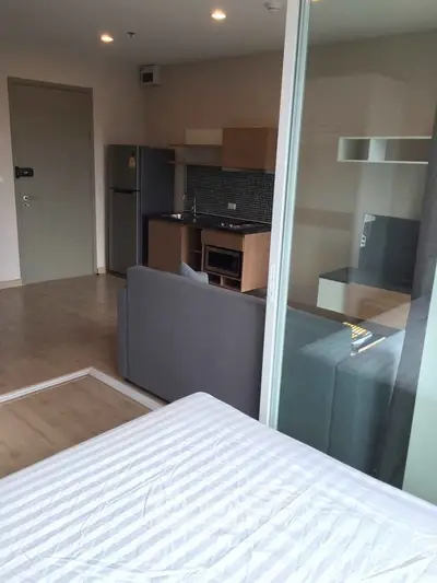 Modern studio apartment with open kitchen and cozy living area, featuring sleek appliances and stylish decor.