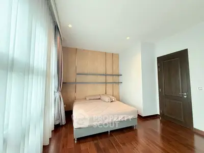 Spacious bedroom with wooden flooring and large window in modern apartment