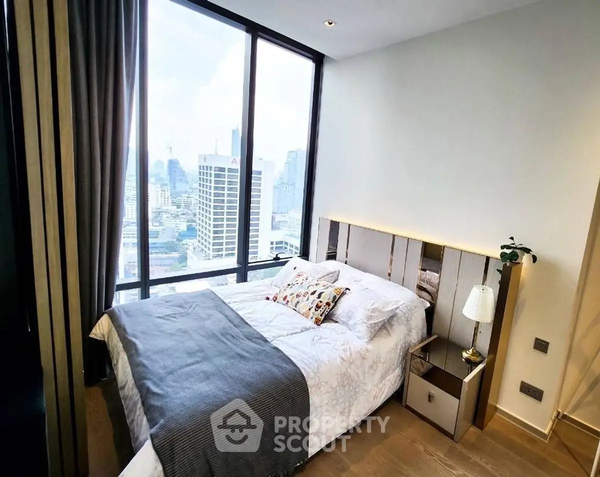 Modern bedroom with city view, featuring cozy bed and large windows.