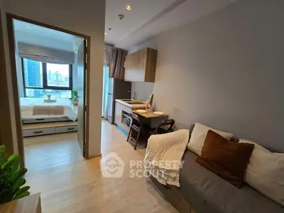 Modern studio apartment with cozy living area and compact kitchen, featuring a view of the city skyline.
