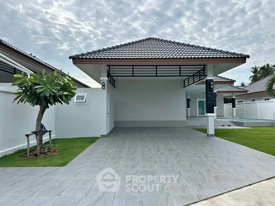 Modern single-story home with spacious driveway and tiled roof, featuring a lush green lawn and a private pool.