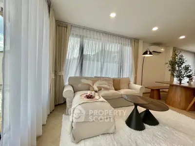 Elegant living room with plush sofa, modern coffee table, and natural light through large windows.