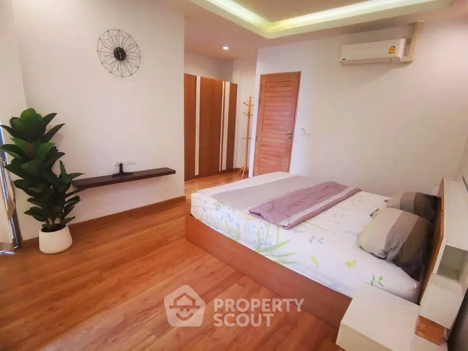Spacious modern bedroom with wooden flooring and stylish decor