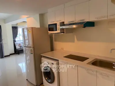 Modern kitchen with appliances including washing machine and microwave in a bright apartment.