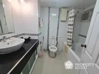 Modern bathroom with sleek fixtures, including a wall-mounted sink, toilet, and bathtub with a chic striped shower curtain.