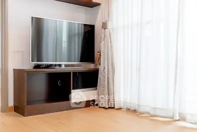 Modern living room with sleek TV stand and large window draped with elegant curtains.