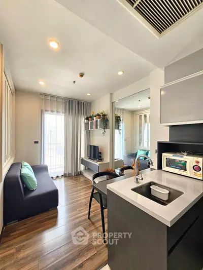 Modern open-layout living room with kitchen, featuring sleek design and natural light.