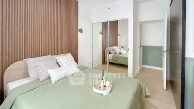 Modern bedroom with stylish decor and mirrored closet doors, featuring a cozy bed with green bedding.