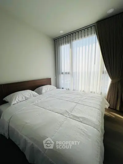 Bright and airy bedroom with large window and elegant curtains