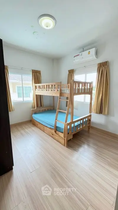 Bright bedroom with wooden bunk bed and large windows in modern home.