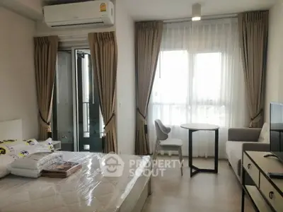 Modern bedroom with large windows, elegant curtains, and a cozy seating area in a stylish apartment.