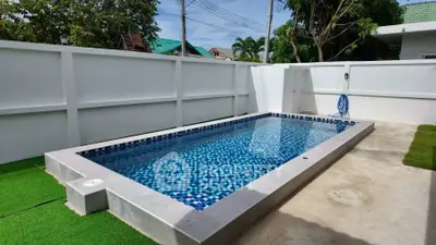 Modern backyard pool with privacy fence and lush greenery