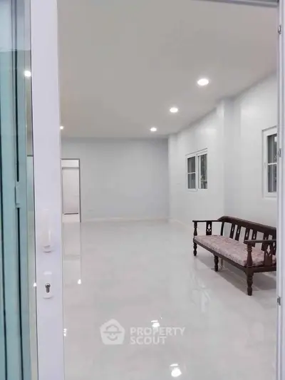 Spacious empty living room with modern lighting and classic wooden bench.