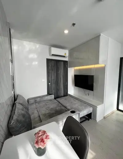 Modern living room with sleek furniture and wall-mounted TV in a stylish apartment.