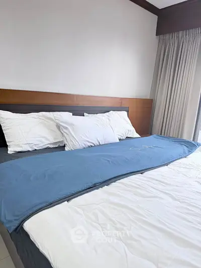 Spacious bedroom with elegant bedding and natural light, perfect for relaxation and comfort.