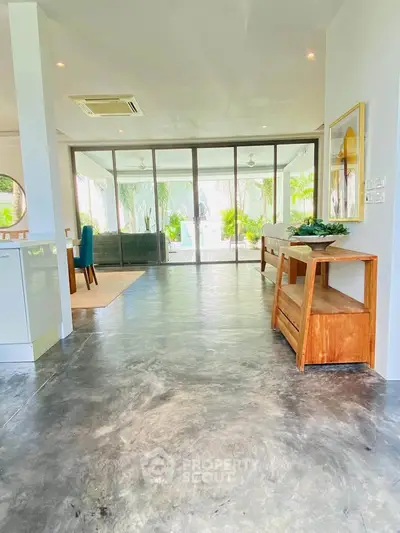 Spacious open-plan living area with large glass doors leading to a lush garden view, perfect for modern living.