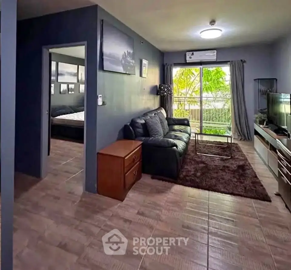 Spacious living room with modern decor and large window offering lush garden views.