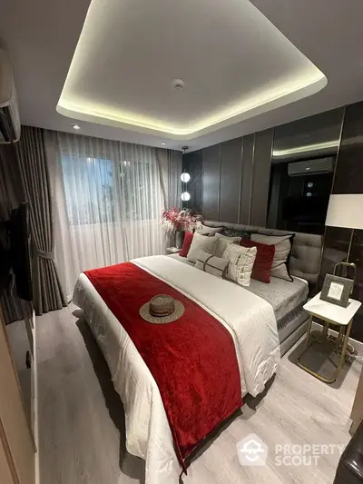 Luxurious modern bedroom with elegant decor and ambient lighting, featuring a plush bed with red accents and stylish furnishings.