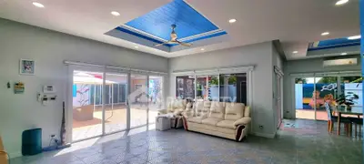 Spacious living room with modern design and large windows opening to a vibrant patio.