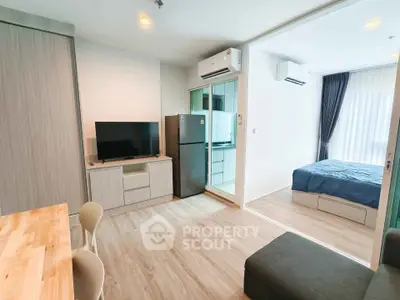 Modern apartment interior with open living room and bedroom, featuring sleek furniture and natural light.