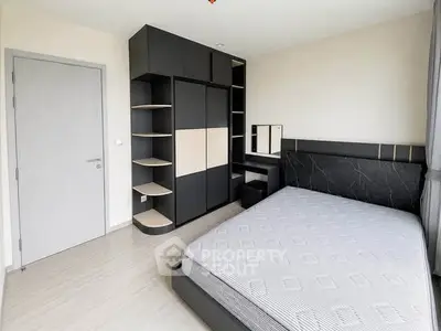 Modern bedroom with sleek black furniture and large window for natural light.
