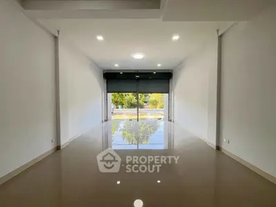 Spacious empty room with glossy tiled floor and large window view.