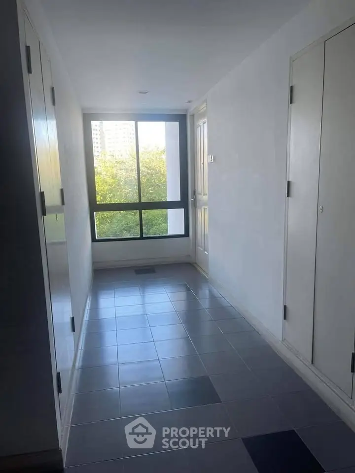 Bright corridor with large window and tiled floor in modern building