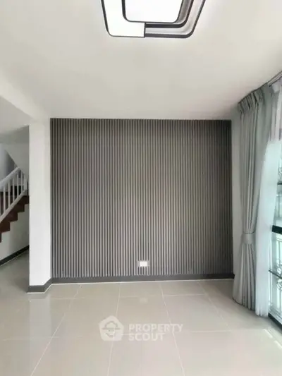 Modern living room with stylish wall paneling and large window for natural light.