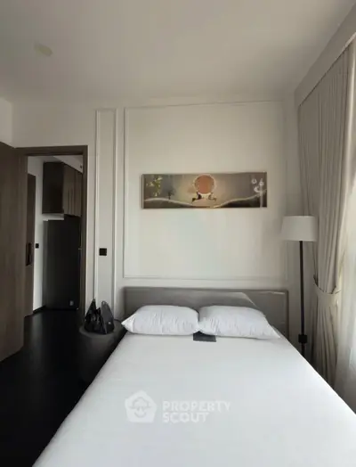 Modern bedroom with elegant decor and natural light, featuring a stylish bed and contemporary artwork.