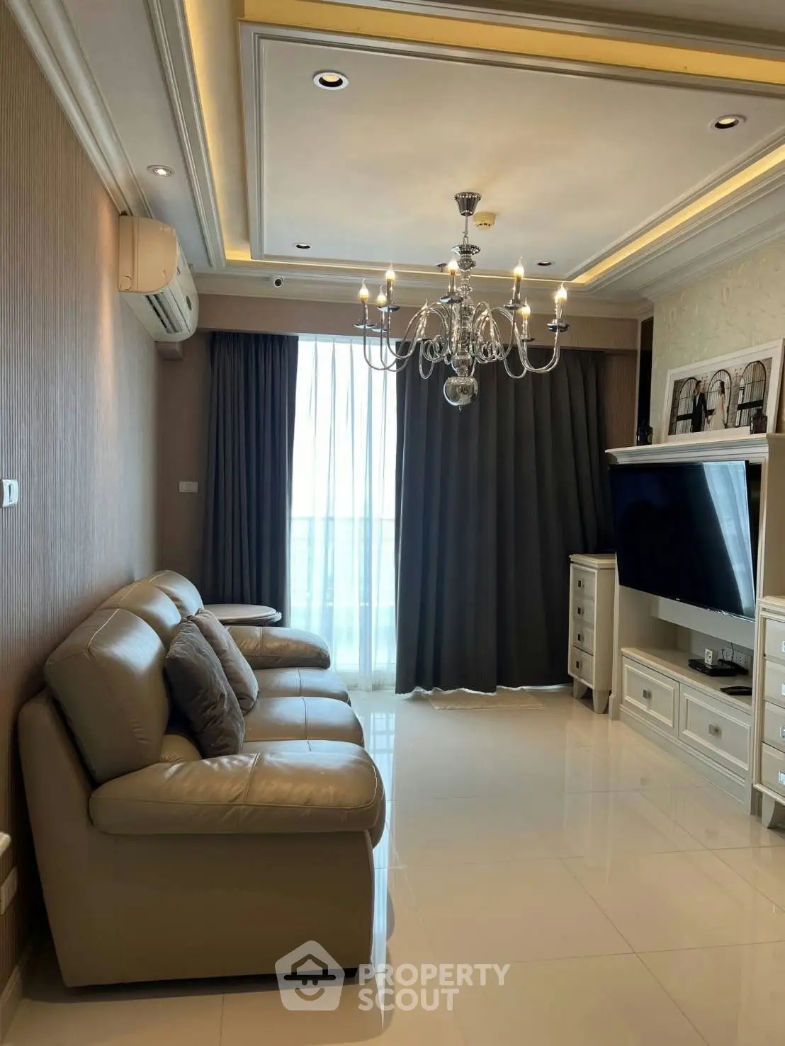 Luxurious living room with elegant chandelier and modern leather sofa, perfect for stylish urban living.
