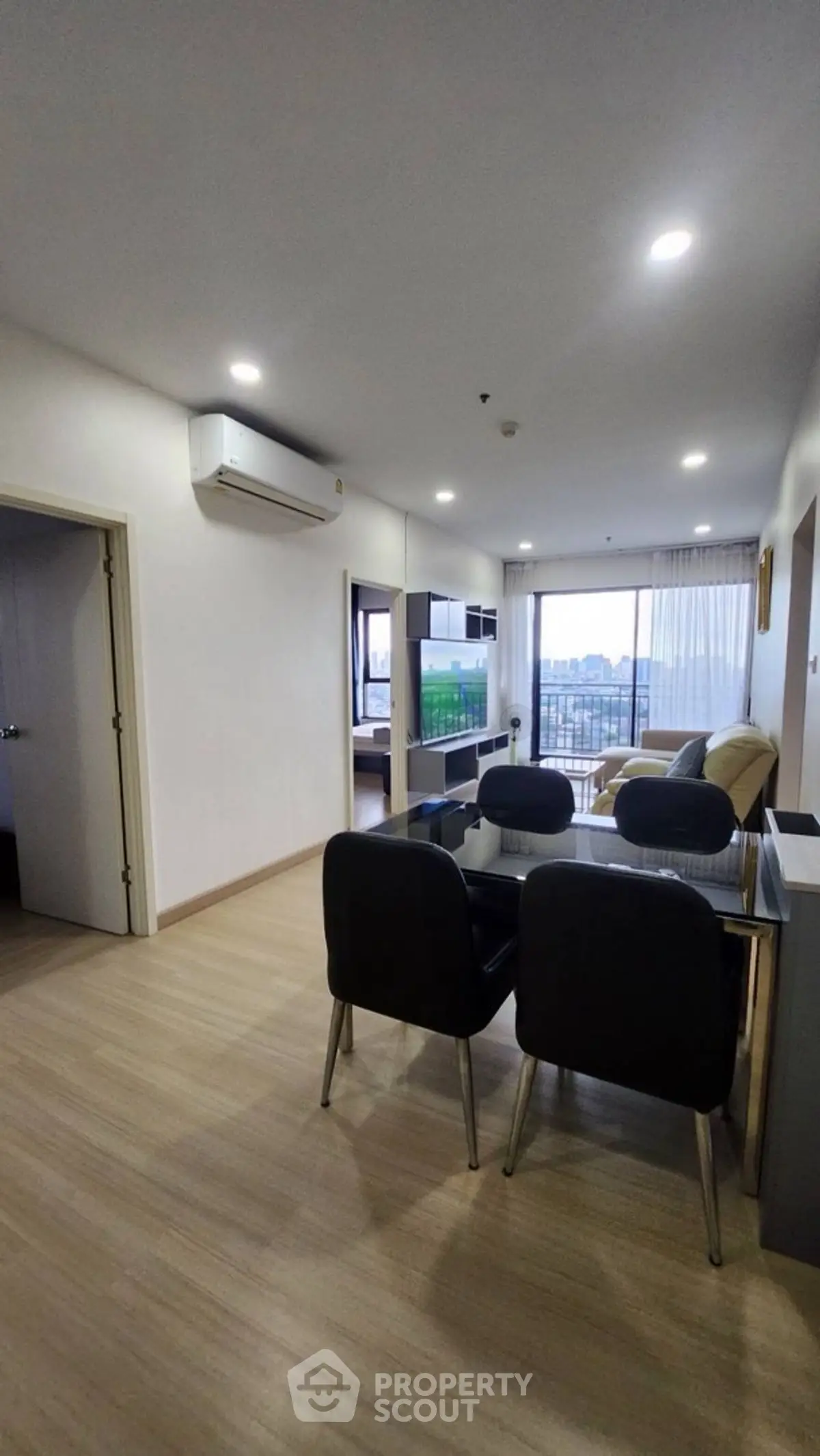 Modern open-plan living room with dining area and city view balcony